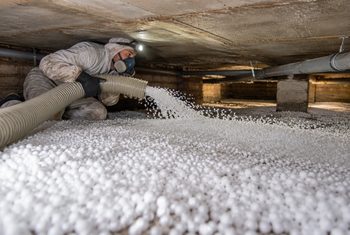 Monteur brengt EPS-parels aan op de bodem van een kruipruimte voor bodemisolatie